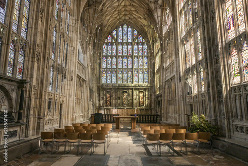 Gloucester, United Kingdom - 21 July 2026: View of the interior of Gloucester Cathedral with its ornate stained glass windows, stone vaulted ceiling, and rows of wooden chairs.