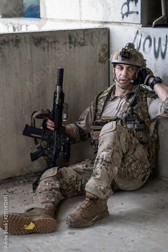 Foto Special force soldier operative sit on ground talk on radio handset during operation