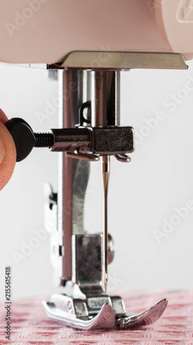 Obraz na płótnie Close up of human hand adjusting metal needle of sewing machine with presser foo
