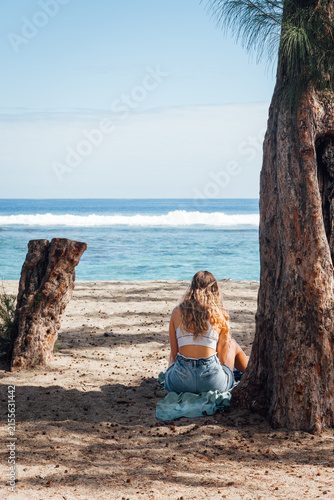 Jeune femme assise sur une plage. Touriste en vacances à la mer. Femme blonde sur l'île de La Réunion. Vacances en été