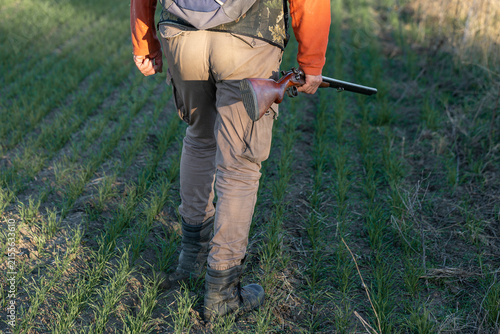 A hunter with a gun in camouflage clothing. A gentleman with a gun, medium shot, unrecognizable.