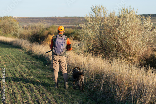 A hunter with a gun in camouflage clothing. A gentleman with a gun, medium shot, unrecognizable.