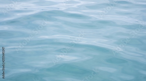 Calm water liquid surface background with soft gentle ripples and natural light reflection serene peaceful atmosphere high detail texture large negative space ideal for wellness spa and tranquil