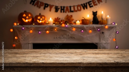 Rustic wooden table mockup with blurred Halloween fireplace, spooky holiday background with carved pumpkins and candles
