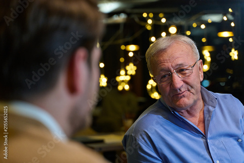 Konstfotografi Elderly Man Conversing With Younger Person In Cozy Cafe With Festive Bokeh Light