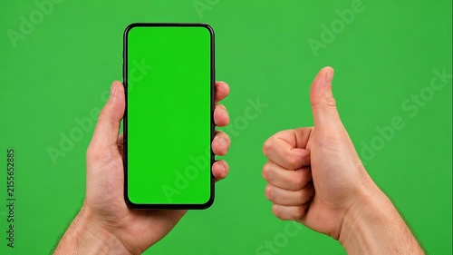 Holding smartphone with green screen and showing thumbs up gesture