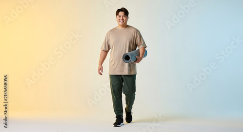 Curvy body positive male model carrying yoga mat on gradient background