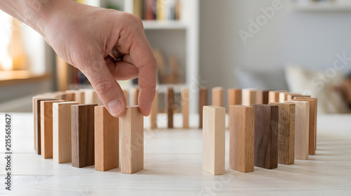 A hand placing a wooden domino block in a circle on a table