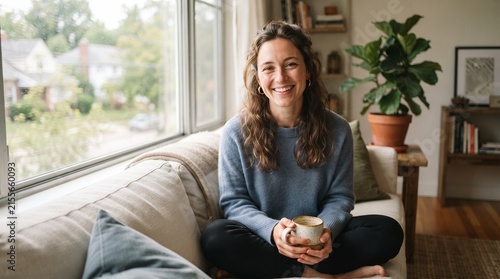 Woman eating apple on couch in bright living room.