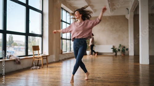 Young woman dancing joyfully in bright studio space.