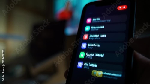 Hand holding smartphone in the dark receiving a lot of notifications