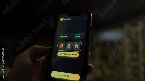 Hand holding smartphone with slot machine app showing jackpot win in the dark