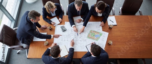 Business meeting with architects discussing building plans and site layouts in a modern conference room with professionals examining architectural