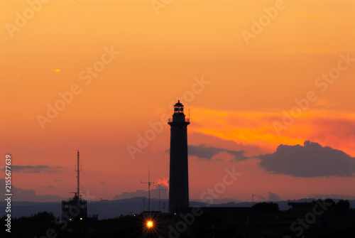 Faro silhouette al tramonto con cielo arancione infuocato