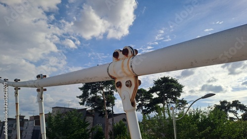 rusty metal joints and bolts on a white bridge structure against a blue sky