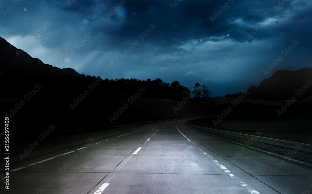 Obraz premium dark night road through forest and mountains, rain and storm