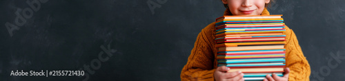  young schoolboy with messy light brown hair, standing on the right side of the frame, peeking over a tall stack of colorful books that he holds in his hands, 