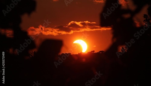 Solar eclipse with clouds and leaves