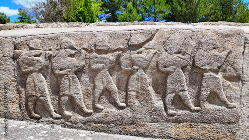 Obraz na plátně Ancient Hittite orthostat relief wall depicting a chariot wheel, lute players, and acrobats at the Alacahöyük archaeological site, Turkey