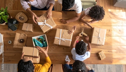 Family wrapping presents together on a wooden table for holidays.