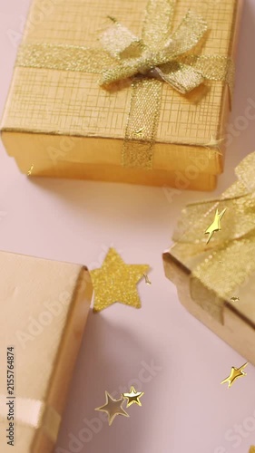 Multiple golden star icons floating against christmas gifts on white surface