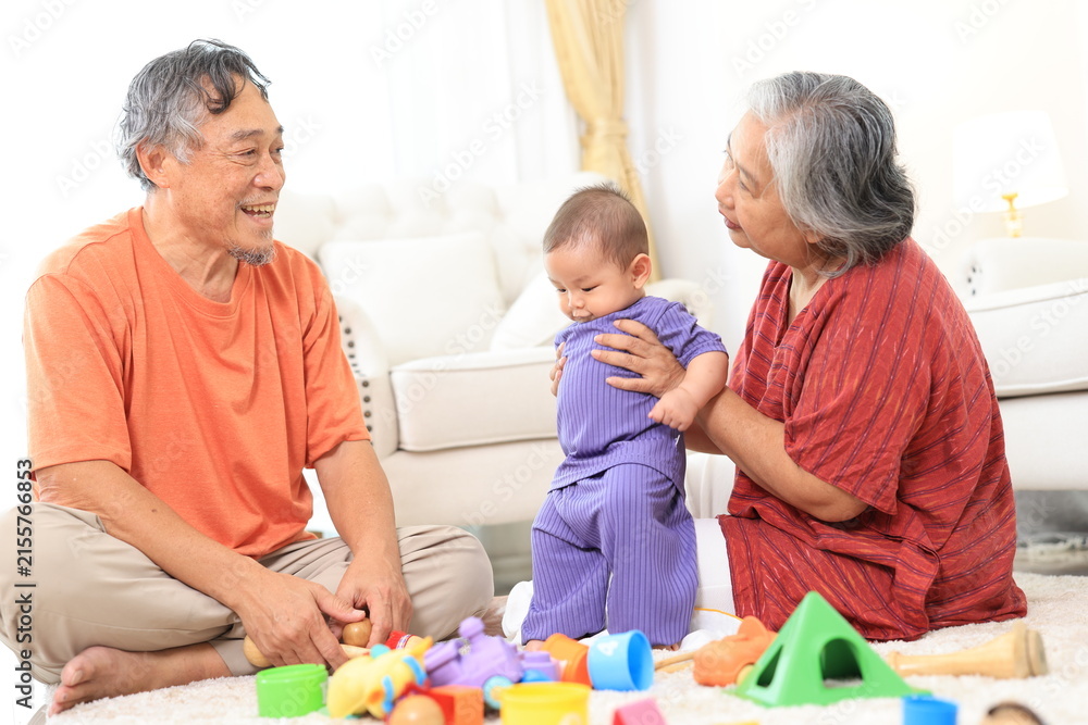 Obraz premium Asian family grandmother, grandfather ,son playing with colorful kid toys. Happy baby boy in kindergarten or daycare. Child playing with colorful educational toys at home. Asian woman. Happy family.