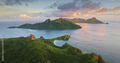 Aerial view of lush green islands surrounded by the blue ocean with rocky outcrops and soft sunset light, Savusavu, Northern Division, Fiji.