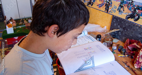 Focused child doing schoolwork surrounded by toys and books
