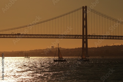 Quadro su tela Lisbon, Portugal - August 12, 2026: Crowds in eclipse glasses watch a partial solar eclipse at sunset near the 25 de Abril Bridge and Praça do Comércio