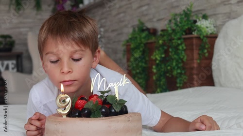 Cute preschool boy with birthday cake with candles at home, preparing for party with friends and siblings