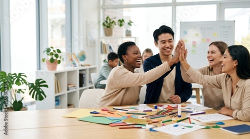 Diverse group of happy young professionals celebrating success with a high five in a modern bright office.