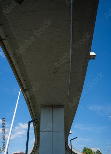 Modern concrete overpass and bridge pillars from low angle view Underneath view of massive concrete viaduct and support columns against blue sky