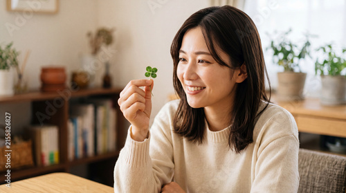 四つ葉のクローバーを見せる楽しそうな女性。アジア人、日本人