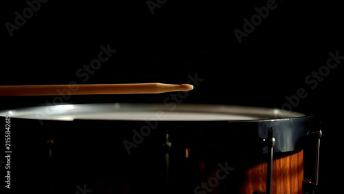 Drumstick poised just above the skin of a timpani drum.