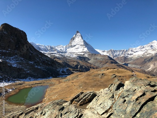 Canvas Print Snow-covered Matterhorn reflected in a calm alpine lake beneath a clear blue sky near Zermatt in the Swiss Alps, Switzerland