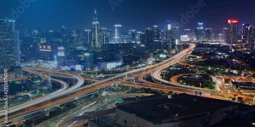 Aerial view of elevated highway interchange at night with city skyline interchange metropolis junction infrastructure exposure transportation downtown vehicles architecture nightlife