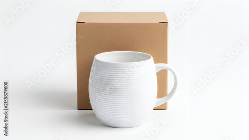 White ceramic mug placed in front of a brown cardboard box isolated on white background