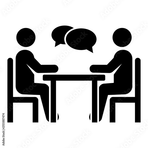 Two people sitting at a table talking in conversation