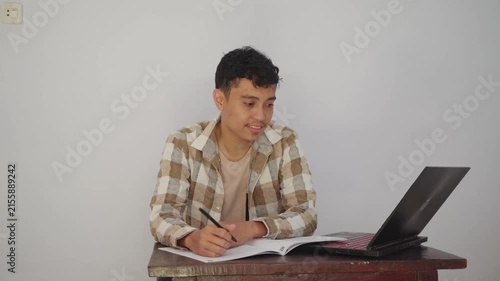 A young man expresses various emotions while studying at a desk, showcasing concentration and frustration.