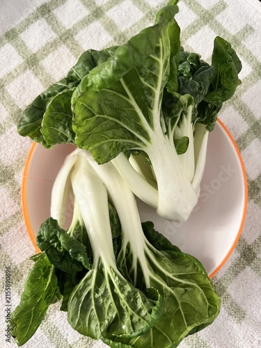 Quadro su tela Fresh bok choy pak choi on white plate with green checkered tablecloth