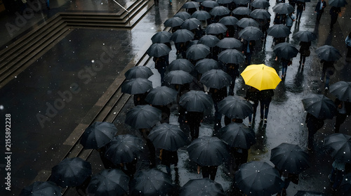 crowd with black umbrellas and yellow umbrella walking through rain