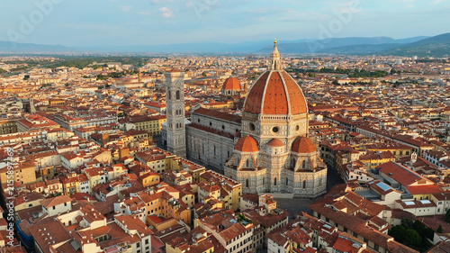 Close aerial drone view of Florence Duomo cathedral dome illuminated by golden sunrise light surrounded by red terracotta roofs and Tuscan hills summer trip Italy