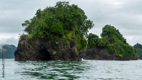 Scenic view of small rocky islands covered with lush green tropical vegetation rising from the sea under a cloudy sky