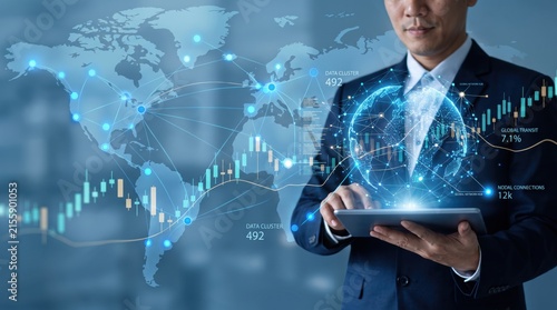 Businessman using tablet with holographic globe and world map network connections, financial stock market charts and data clusters visualization for international trade and global