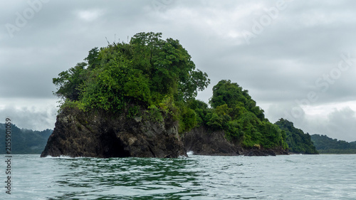 Scenic view of small rocky islands covered with lush green tropical vegetation rising from the sea under a cloudy sky