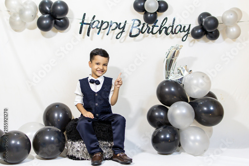Smiling Young Boy Pointing at Happy Birthday Banner During Birthday Celebration