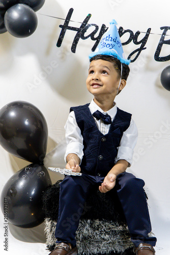 Cute Boy Wearing Party Hat And Formal Clothes At Birthday Celebration playing with bubbles