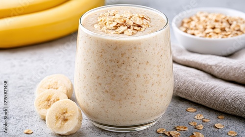 Healthy banana oat smoothie in a glass with rolled oats and sliced bananas. Great for fitness and breakfast nutrition.