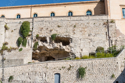 Rock face with natural caves and cavities beneath the Castle of the Counts of Modica, also known as A Rutta ri Cancedda, in the Modica Alta district of Modica, Sicily, Italy.