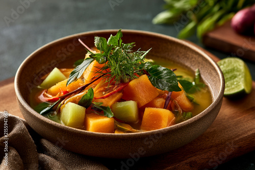 A vibrant bowl of fresh vegetable soup with colorful ingredients and herbs.